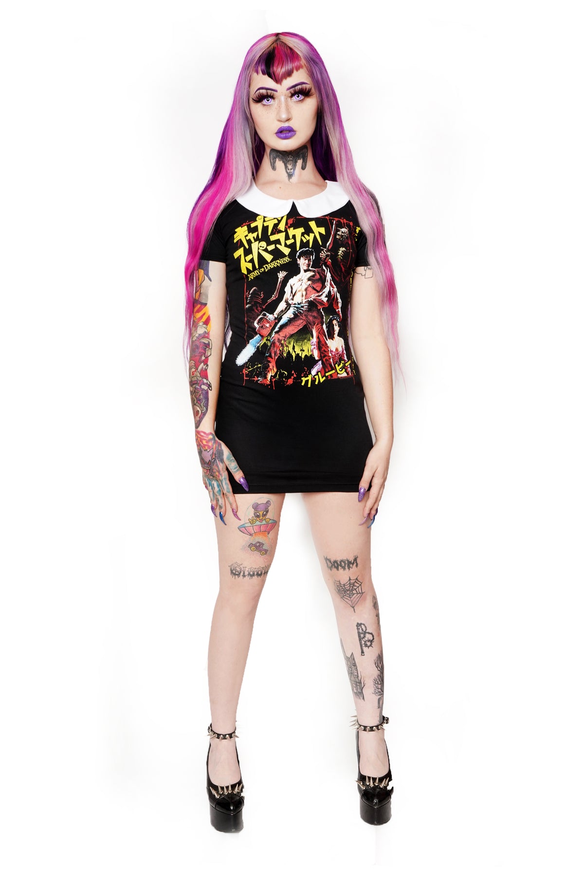 Black short sleeve mini dress with white collar. Features image of man carrying a chainsaw with woman to her knees holding his leg. Battle and castle appear in the background. Yellow inscription in Japanese.