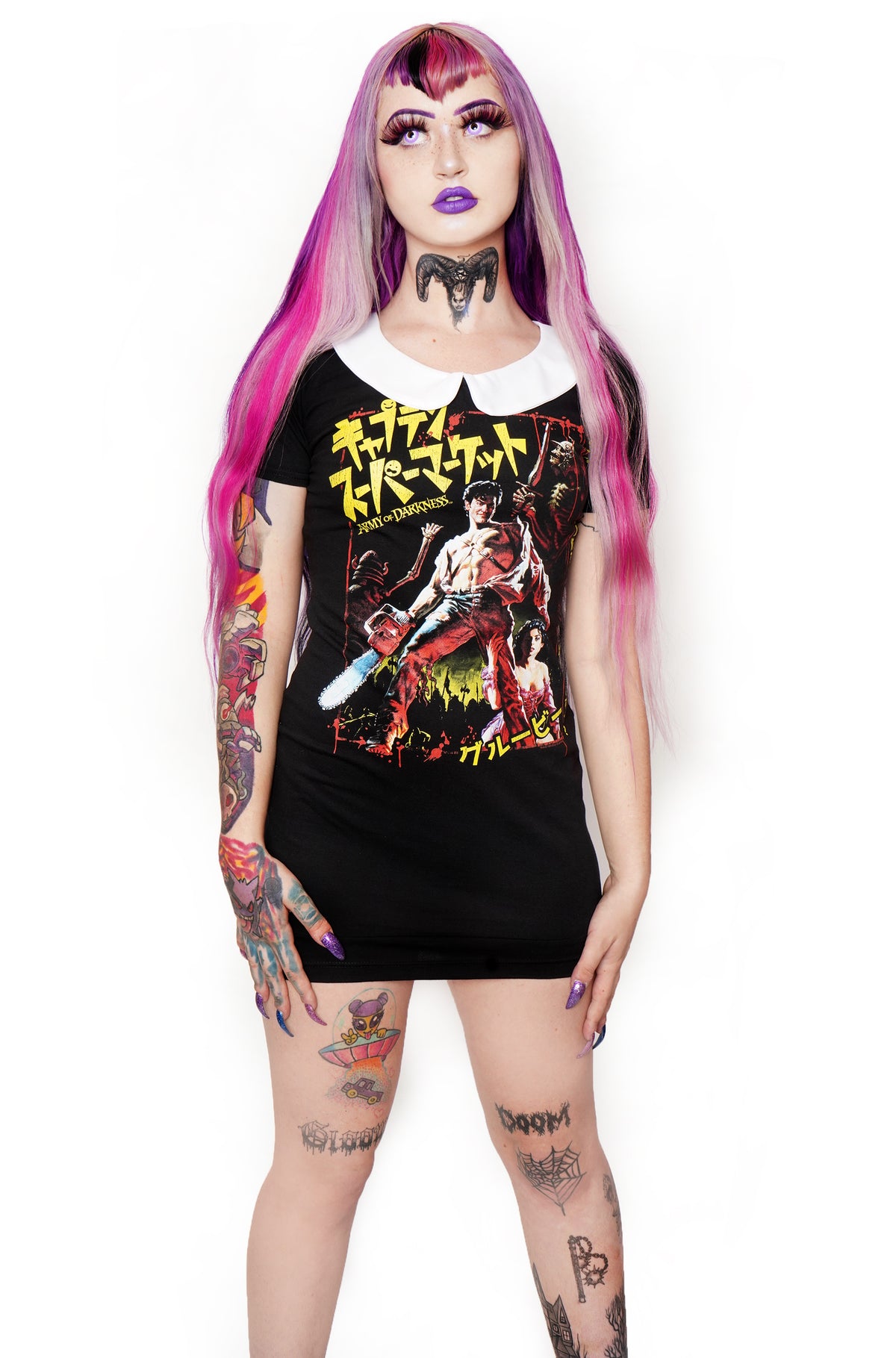 Black short sleeve mini dress with white collar. Features image of man carrying a chainsaw with woman to her knees holding his leg. Battle and castle appear in the background. Yellow inscription in Japanese.