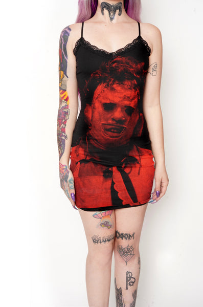 Black thin strap mini dress with black lace trim neckline. Features red print of Leatherface from the movie Texas Chainsaw Massacre in mask.