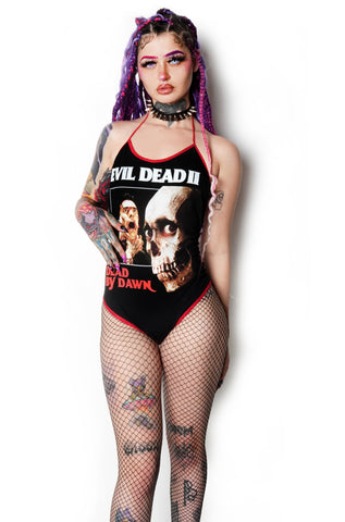 Black bodysuit with red trim and red thin straps to tie around neck. Features picture of a skull and a man being choked by a severed hand. Inscription reads "Dead by Dawn" in red and "Evil Dead 2" in white font.