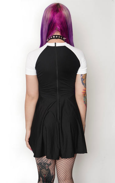 Back of black baby doll style dress wth white short sleeves and white trim neckline. Black zipper along back of dress.