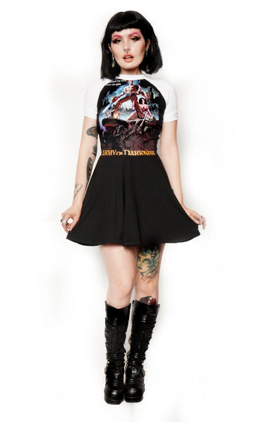 Solid black baby doll style dress with white baseball short sleeves and white trim neckline. Features image of man carrying a chainsaw with woman to her knees holding his leg. Battle and castle appear in the background. Inscription reads "Army of Darkness" in yellow.