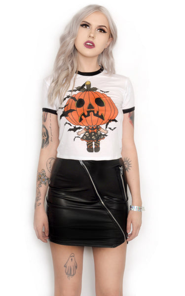 White ringer shirt with black trim. Features jack o lantern head wearing a dress with skulls and orange trim, orange collar and orange bow. Black bats flying around.