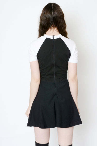 Back view of black baby doll dress with white short sleeves and white trim neckline. Zipper on back of dress.