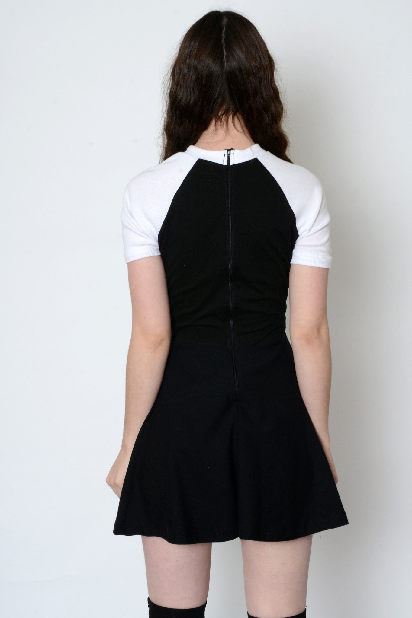 Back of black baby doll dress with white baseball short sleeves and sipper on back