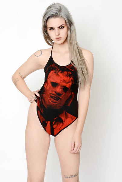 Black bodysuit with black thin straps that tie around neck. Features red print of Leatherface from the movie Texas Chainsaw Massacre in mask.