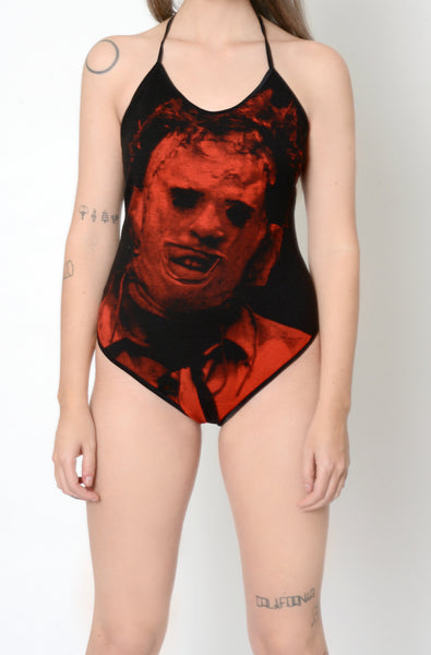 Black bodysuit with black thin straps that tie around neck. Features red print of Leatherface from the movie Texas Chainsaw Massacre in mask.