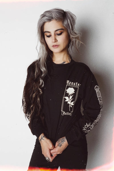 Black long sleeve white rose on left chest area with "Monster Tattoo" in white font. The sleeves have a print of ball and chain