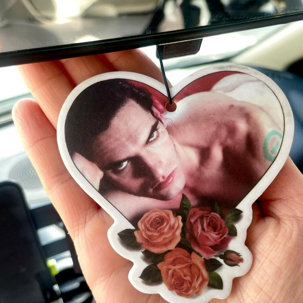 Heart shaped air freshener with white elastic band. Features image of Peter Steele laying in bed with red sheets. Roses at bottom of heart.