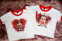 solid white ringer tee with red trim and American Psycho print. Man holding chainsaw in red heart with blood. Alternate print of man with blood behind him also shown