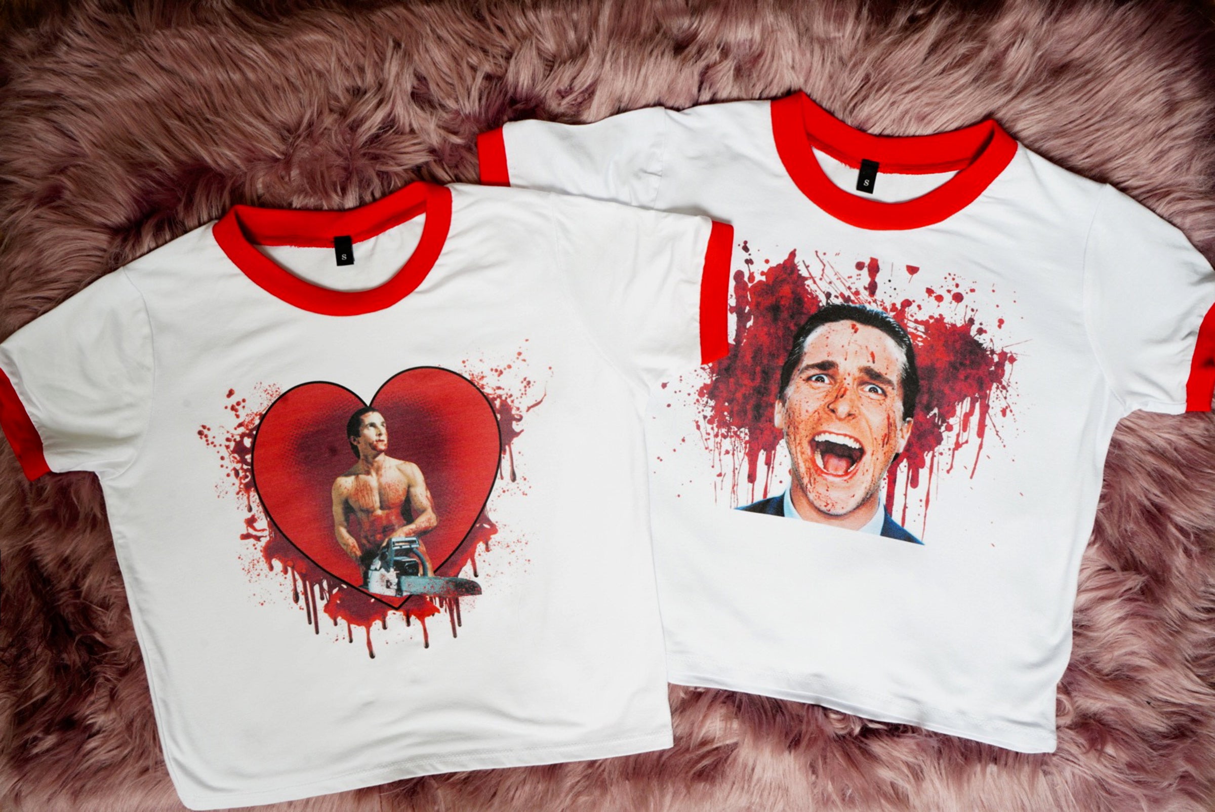 solid white ringer tee with red trim and American Psycho print. Man holding chainsaw in red heart with blood. Alternate print of man with blood behind him also shown