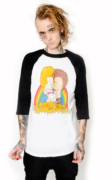 White baseball tee with black sleeves and black trim neckline. Features Beavis and Butthead kissing in front of a rainbow. Inscription reads "BEAVIS AND BUTTHEAD" in black.