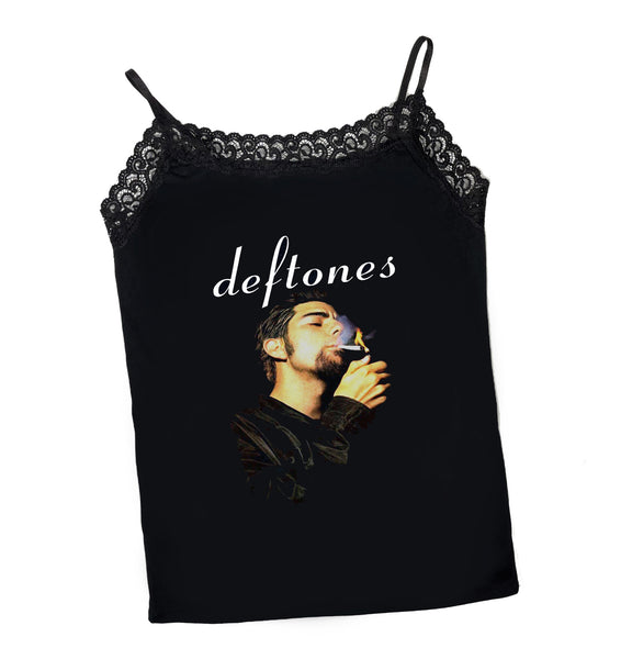 Black thin strap slightly cropped tank top with black lace trim neckline. Print features musician, Chino Moreno, lighting up cigarette. Inscription reads "Deftones" written in white font.