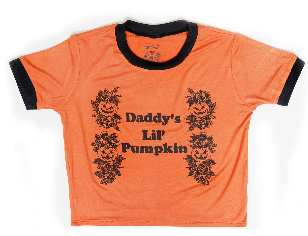 Orange ringer tee with black trim. Black print features pumpkins with leaves and black font that reads " Daddy's Lil' Pumpkin".