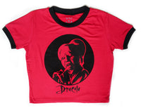 Red ringer tee with black trim. Black print features vampire licking bloody razor. Black font reads "Dracula".