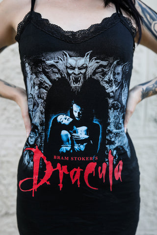 Black mini dress with thin straps and black lace trim neckline. Print features man and woman embracing with gargoyles surrounding. "Bram Stoker's Dracula" is written in red font