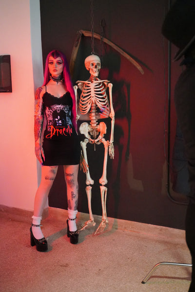 Black dress with thin straps and black lace trim neckline. Print features man and woman embracing with gargoyles surrounding. "Bram Stoker's Dracula" is written in red font