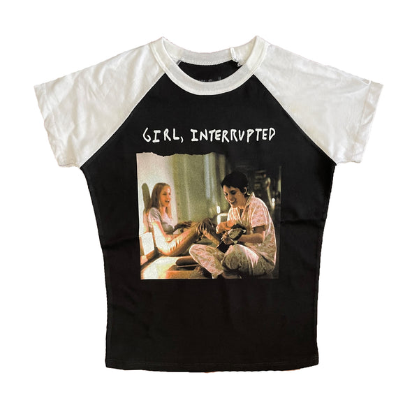 Black baseball tee with white short sleeve and white trim neckline. Features image of 2 girls sitting together, one playing guitar and the other singing. White font reads "Girl, Interrupted"