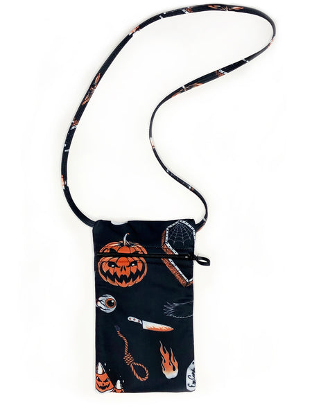 Black mini concert style purse with thin straps and zipper. Print is Halloween pattern containing candy corn, flames, cat, coffins, pumpkins, poison bottle, noose, and crow in black white and orange.