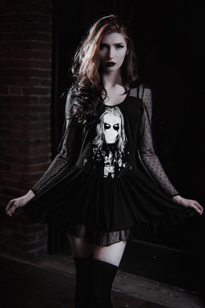 Black ballerina style dress with long sheer sleeves and sheer trim on bottom of skirt. Black and white print shows man with corpse paint.