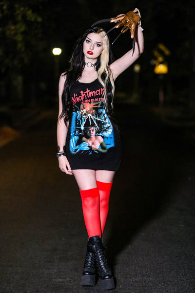 Black thin strap mini dress with black lace neckline. Features image on woman laying in bed under sheets with Freddy Krueger knife hand above her head. Inscription reads "A Nightmare ON ELM STREET" in red.