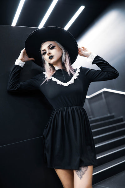 Black long sleeve, high neck, Victorian style dress with white lace trim neckline, cuffs and V shape trim from chest to shoulders. Black zipper down chest from neckline to V lace trim. Dress cinched at waist.