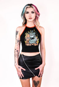 Black halter top with thin orange tie around neck straps and orange trim. Features green witch with an evil smile kneeling by orange pumpkins with yellow flames in background. Inscription reads "Trick or Treat" in orange.