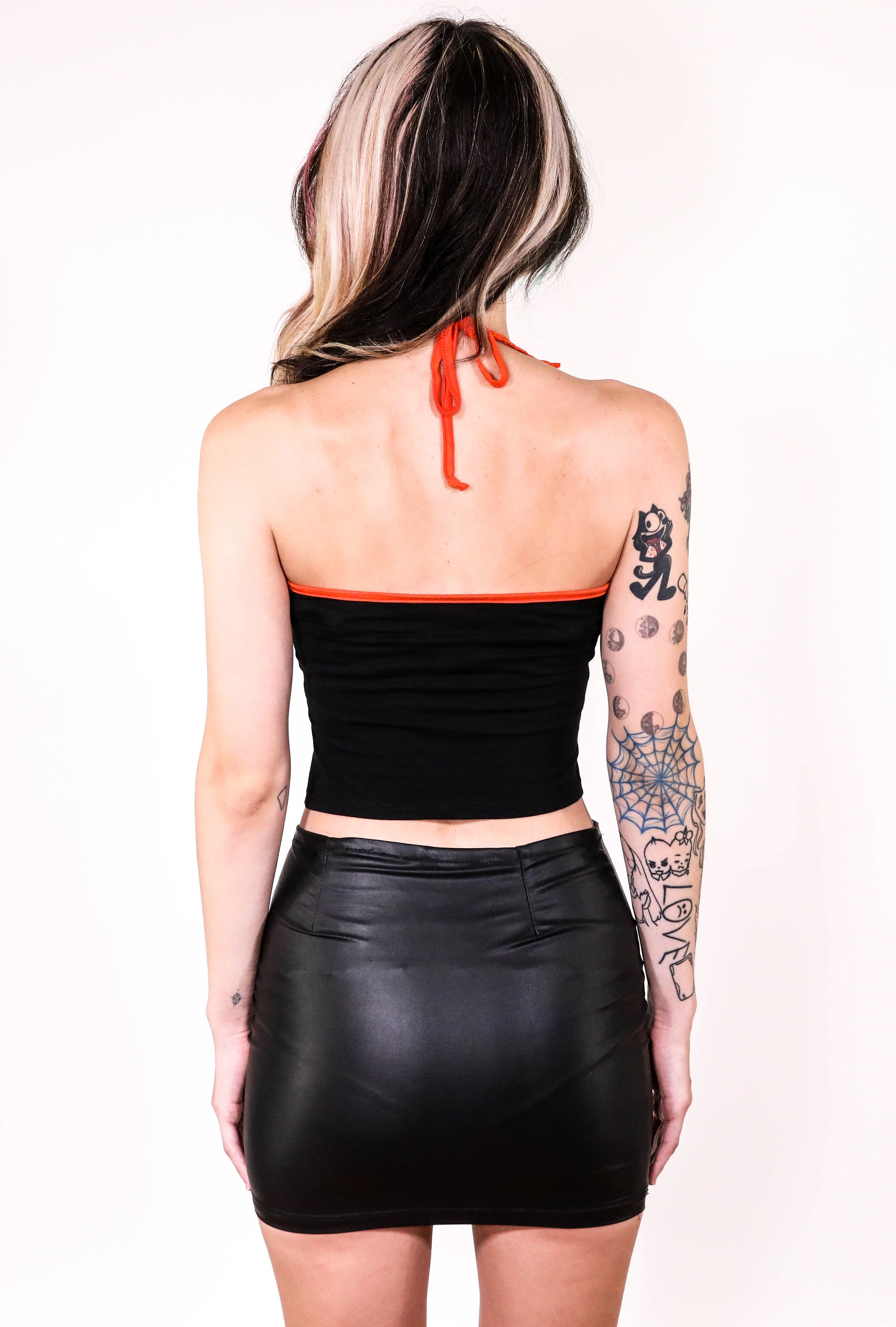 Back of black halter top with thin orange straps that tie around neck and orange trim.