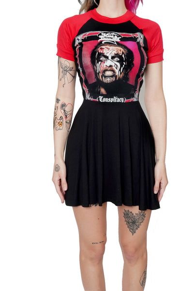 Black baby doll dress with red short sleeves and red trim neckline. Features image of mans face in corpse makeup around red and black square border with red background. Inscription reads "King Diamond" and "Conspiracy" in white.