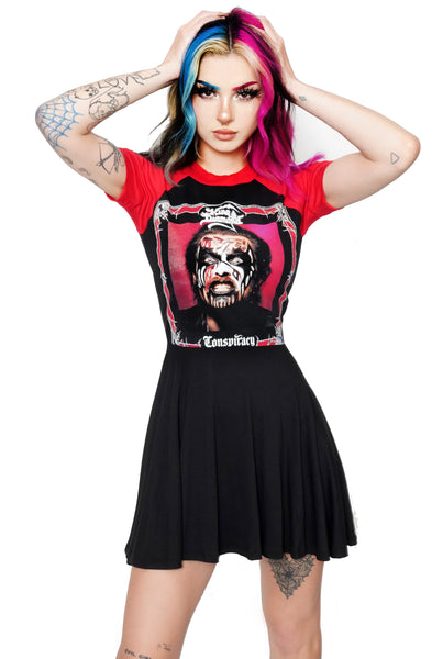 Black baby doll dress with red short sleeves and red trim neckline. Features image of mans face in corpse makeup around red and black square border with red background. Inscription reads "King Diamond" and "Conspiracy" in white.