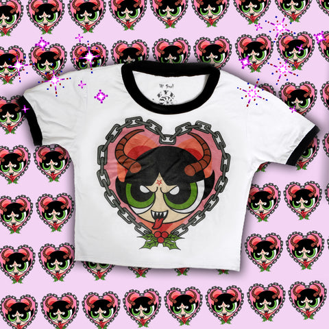 White ringer tee with black trim. Features image of Buttercup from the Powerpuff Girls with pentagram on forehead and horns, sticking her tongue out with sharp teeth. Heart shape chain border around image with mistletoe below.