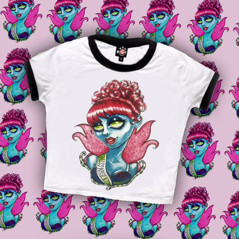 white ringer tee with black trim. Print features blue deceased pageant queen with green eyes and red hair wearing a sash hat reads "MISS ARGENTINA"