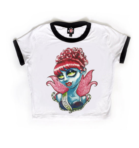 white ringer tee with black trim. Print features blue deceased pageant queen with green eyes and red hair wearing a sash hat reads "MISS ARGENTINA"