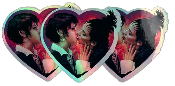 Heart shape holographic vinyl sticker.  Features Nancy from the movie "The Craft" and Lydia from "Beetlejuice" kissing.