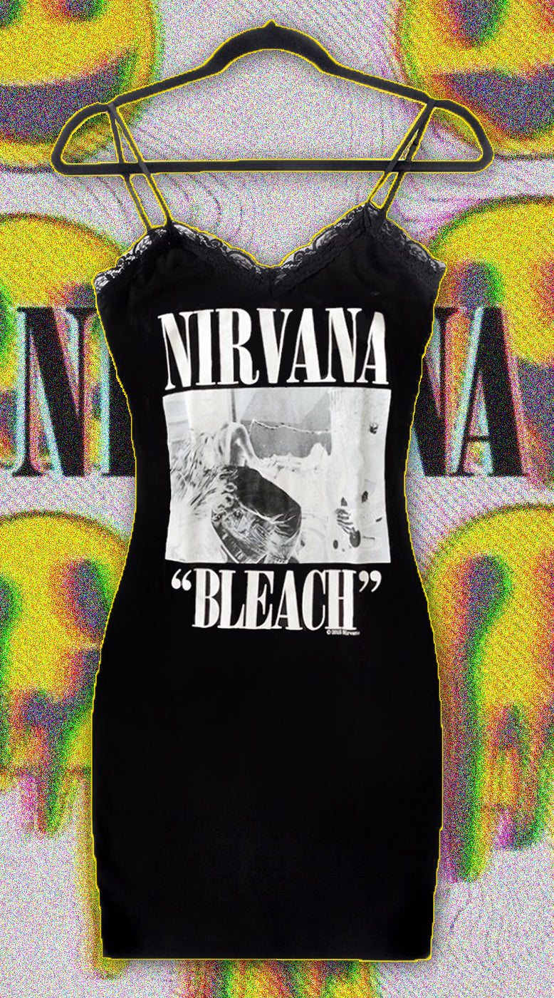 Black thin strap mini dress with black lace trim neck line. White print features image of the band playing guitar and drums. White inscription reads "NIRVANA" and "Bleach"