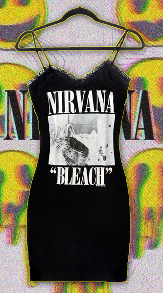 Black thin strap mini dress with black lace trim neck line. White print features image of the band playing guitar and drums. White inscription reads "NIRVANA" and "Bleach"