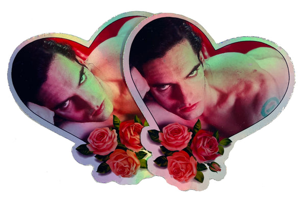Heart shape holographic vinyl sticker. Features image of singer Peter Steele laying topless in bed with red sheets. Roses at bottom of heart.