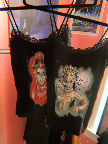 Black thin strap tank with black lace trim neckline. Features green printed image of Queen Akasha from the movie Queen of the Damned with red blood on her lip. Full moon and bats in background.