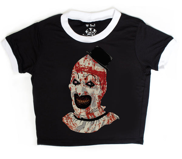Black ringer tee with white trim. Features clown from the movie Terrifier wearing a black top hat with red blood splattered on face.