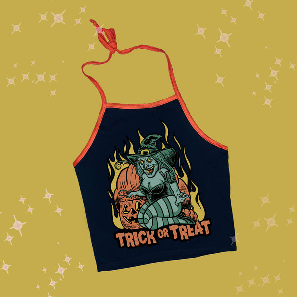 Black halter top with thin orange tie around neck straps and orange trim. Features green witch with an evil smile kneeling by orange pumpkins with yellow flames in background. Inscription reads "Trick or Treat" in orange.